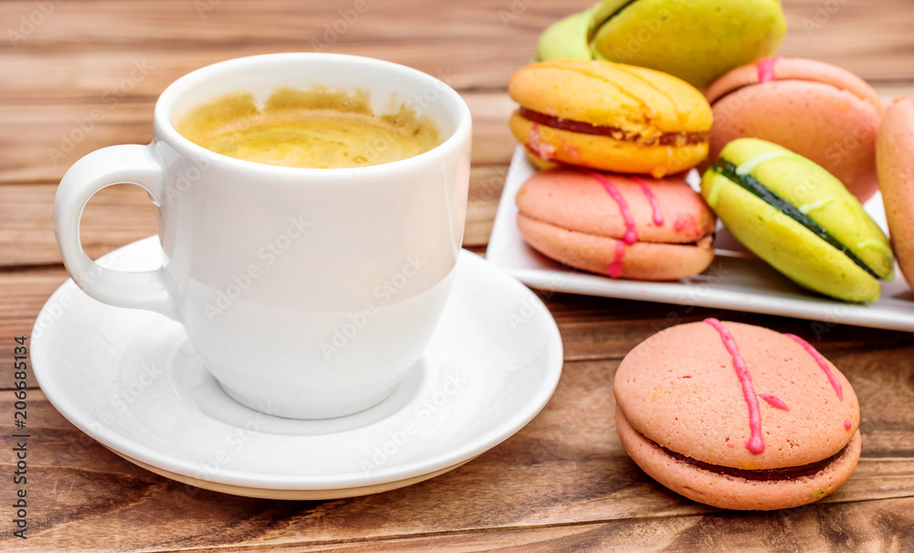 Cup of coffee with colorful macaroons on the wooden table. Cup of coffee with colorful macaroons on the wooden table.