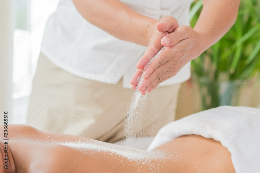 Fototapeta premium Woman enjoying getting a salt scrub beauty treatment at spa.