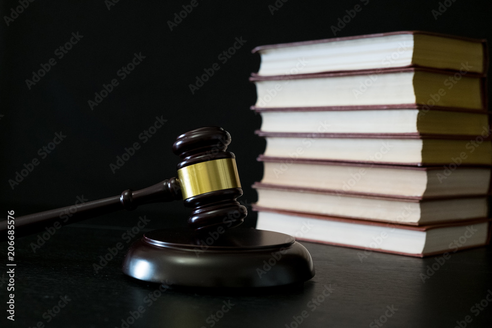 Judge gavel beside pile of books on black wooden background Judge gavel beside pile of books on black wooden background