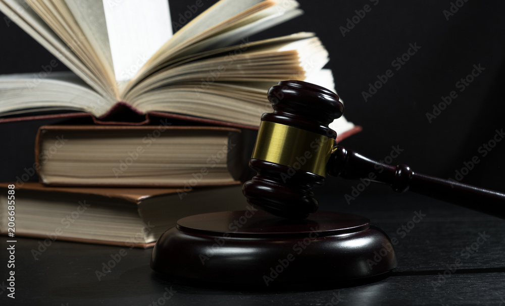 Judge gavel beside pile of books on black wooden background Judge gavel beside pile of books on black wooden background