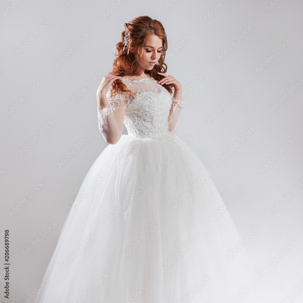 Lovely young woman bride in lavish wedding dress. Light background.