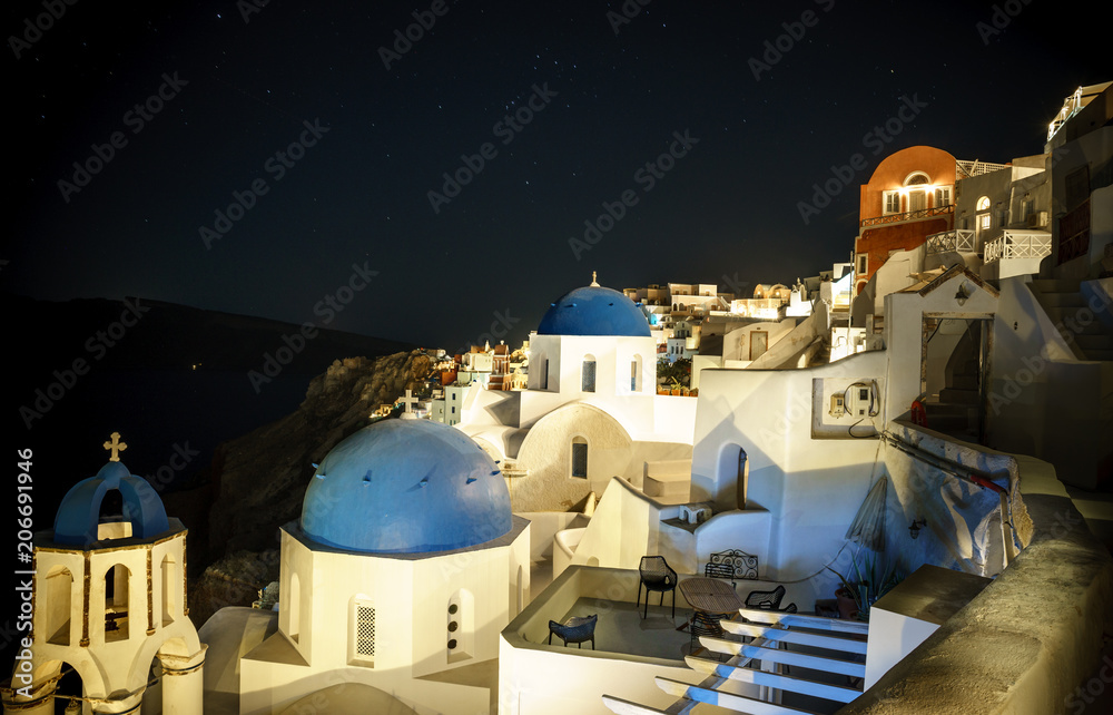 Scenic view of traditional cycladic white houses and blue domes in Oia village, Santorini island, Greece at night