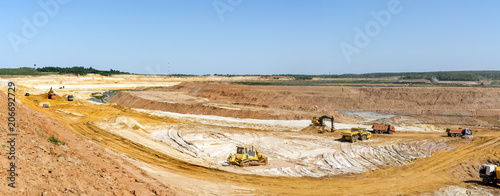 Panorama of the quarry. Extraction of sand in the quarry. Backhoe loading sand into dump trucks.