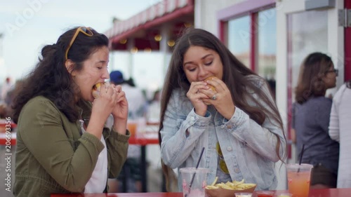 Best Friends Cheers With Their Burgers, Then Really Enjoy Taking First Bite, On Santa Monic Pier (Shot On Red Scarlet-W Dragon In 4K, Slow Motion)