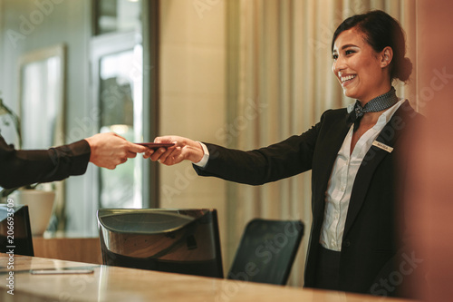 Smiling receptionist attending hotel guest photo