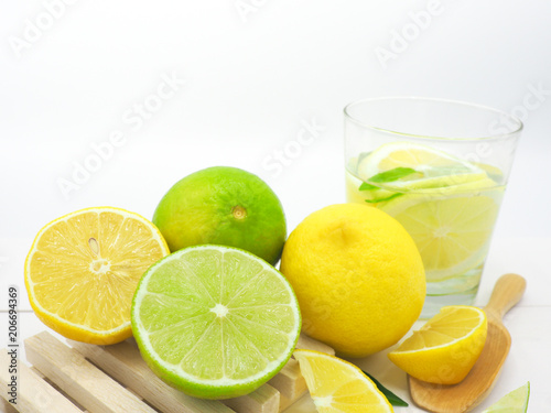 Fresh lemon slice and lime with lemon in water on white wood background
