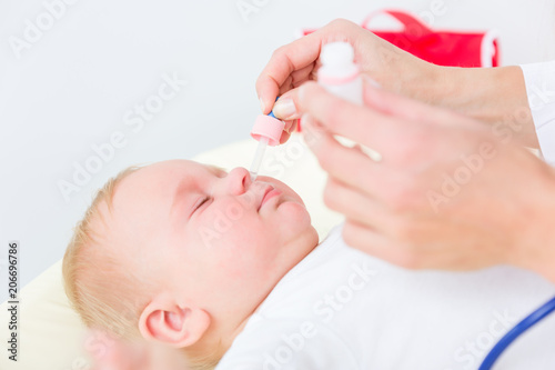 Canvas Print Close-up of the hands of a pediatrician clearing the nose of a baby, by applying