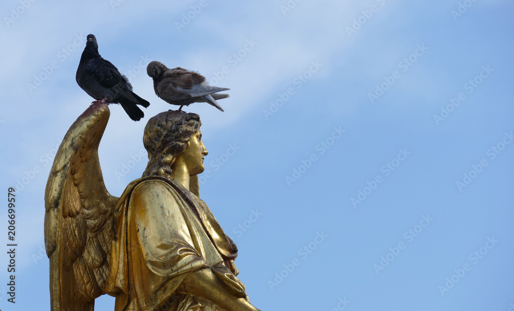 Fototapeta premium Golden angel statue with two doves on the head