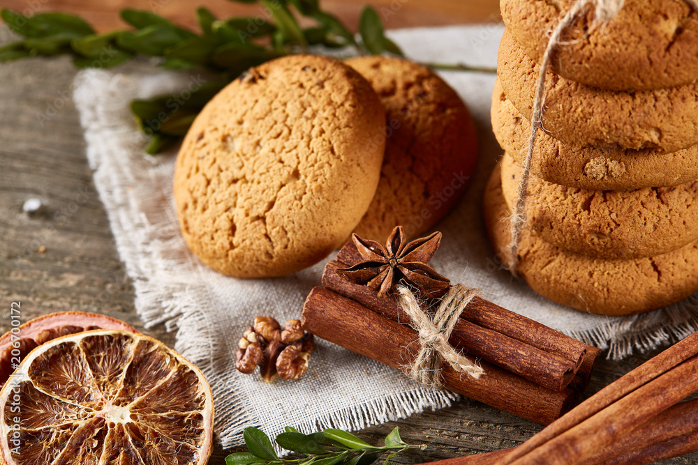 Christmas composition with pile of cookies, cinnamon and dried oranges on light wooden background, close-up. Christmas composition with pile of cookies, cinnamon and dried oranges on light wooden background, close-up.