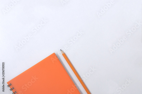Design concept - Top view of orange spiral notebook and color pencil collection on white background. photo