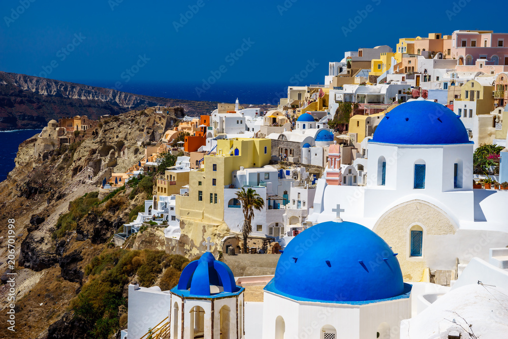 Oia town on Santorini island, Greece. Traditional and famous houses and churches with blue domes over the Caldera, Aegean sea at sunny day