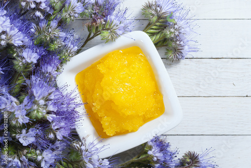Fotografie crystallized phacelia honey and flowers on white wooden background