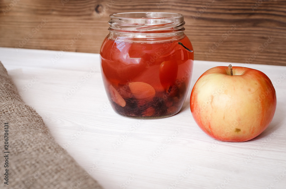 Compote stewed fruit drink in the glass bank with fresh apple on white table background. Compote stewed fruit drink in the glass bank with fresh apple on white table background.