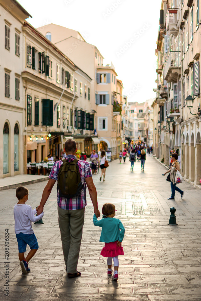 Happy family walking through the Corfu city and holding hands.