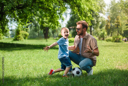 happy father and son with football ball at park
