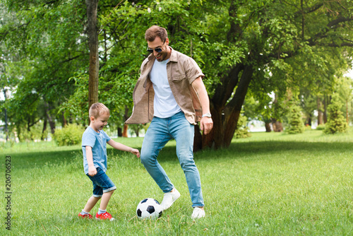 father and son having fun and playing football at park