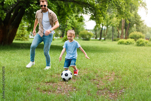 father and son playing football at park