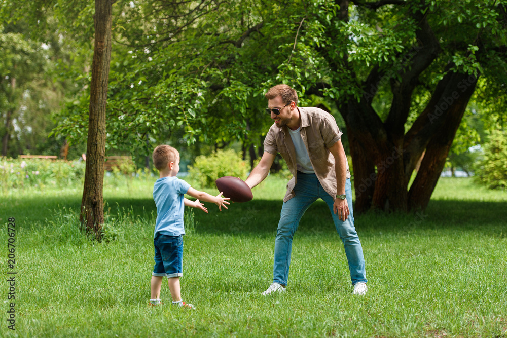 Fototapeta premium happy father and son playing american football at park