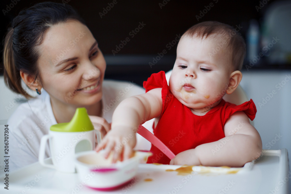 Baby in a red dress is sitting on a child's chair Baby in a red dress is sitting on a child's chair