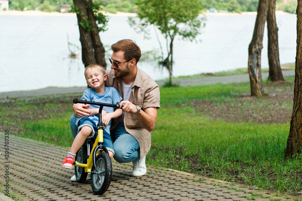 happy father teaching son riding bike at park happy father teaching son riding bike at park