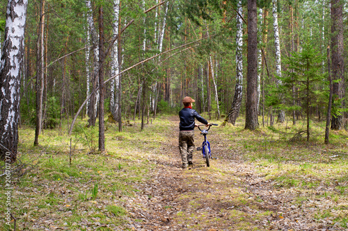 kid with bike walking in the forest
