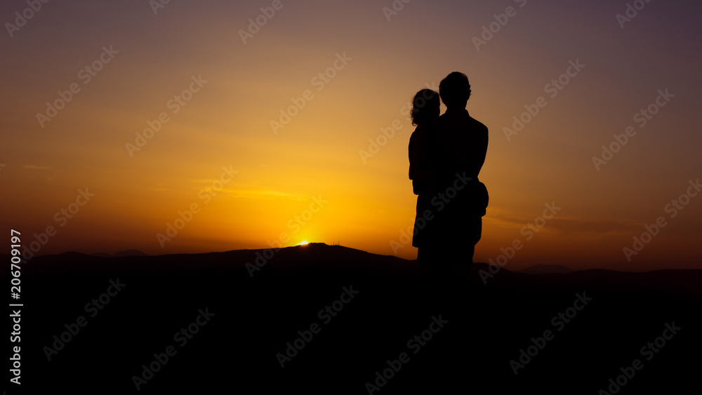 Couple woman man hugs tightly at colorful beautiful sunset with horizon in the background - concept love young romance embrance nature silhouette for ever marriage people old mood feelings holiday