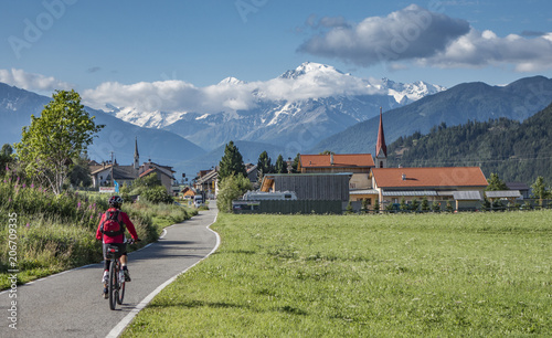 senior woman under way with her e-bike on the famous bicycle route Via Claudia Augusta, Alto adige,Italy, Mount Ortler in the background