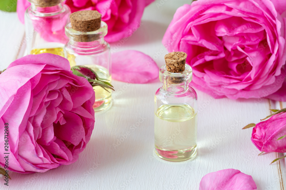 A bottle of essential oil with fresh roses A bottle of essential oil with fresh roses