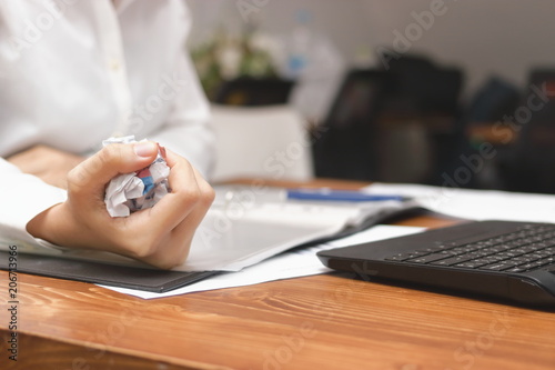 Hands of businesswoman holding crumpled paper on workplace in office. Failure and tired business concept.