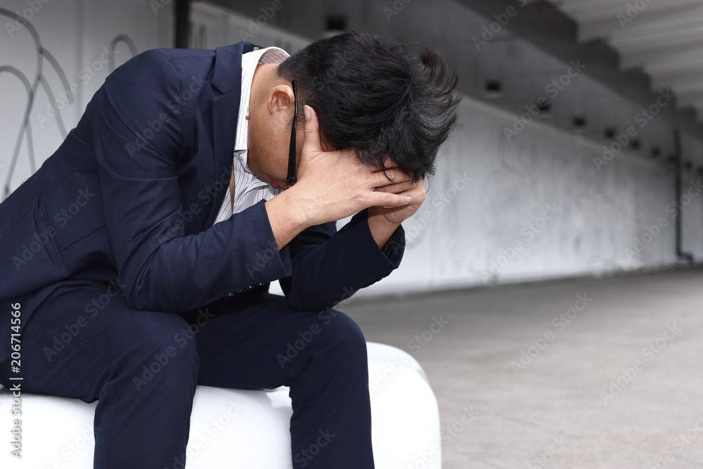 Depressed tired young Asian business man in suit bend down head Depressed tired young Asian business man in suit bend down head