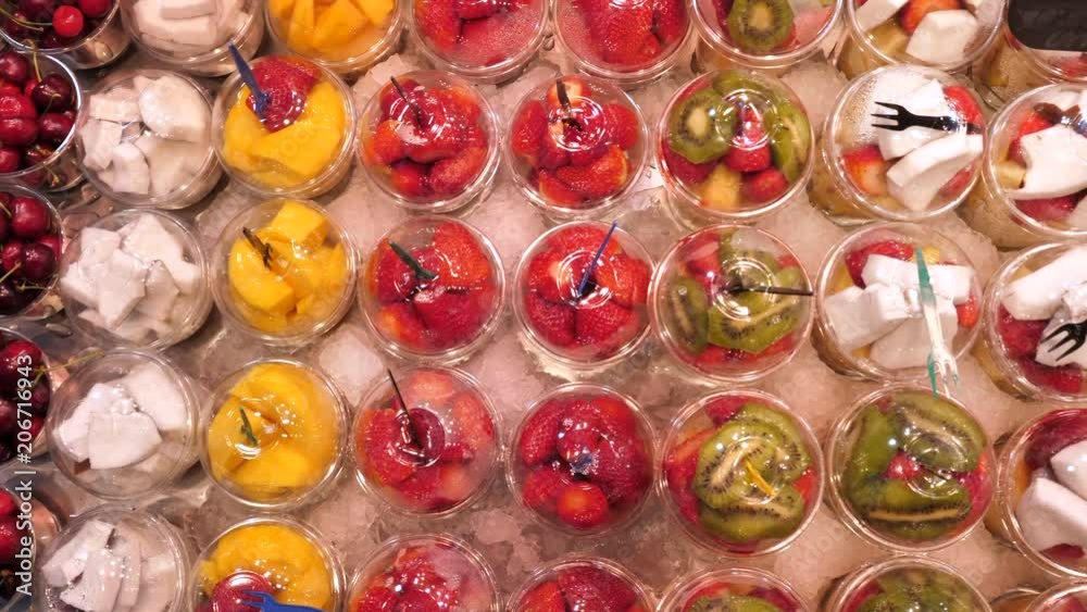 Fresh sliced fruit in plastic cups on a stand at La Boqueria market, Barcelona Fresh sliced fruit in plastic cups on a stand at La Boqueria market, Barcelona