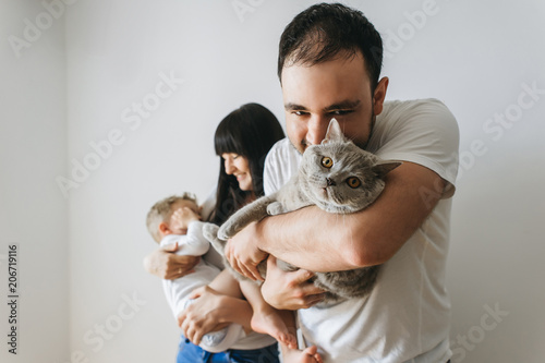 portrait of happy parents holding little toddler boy and grey cat at home
