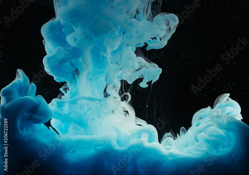 close-up view of bright blue flowing ink on black