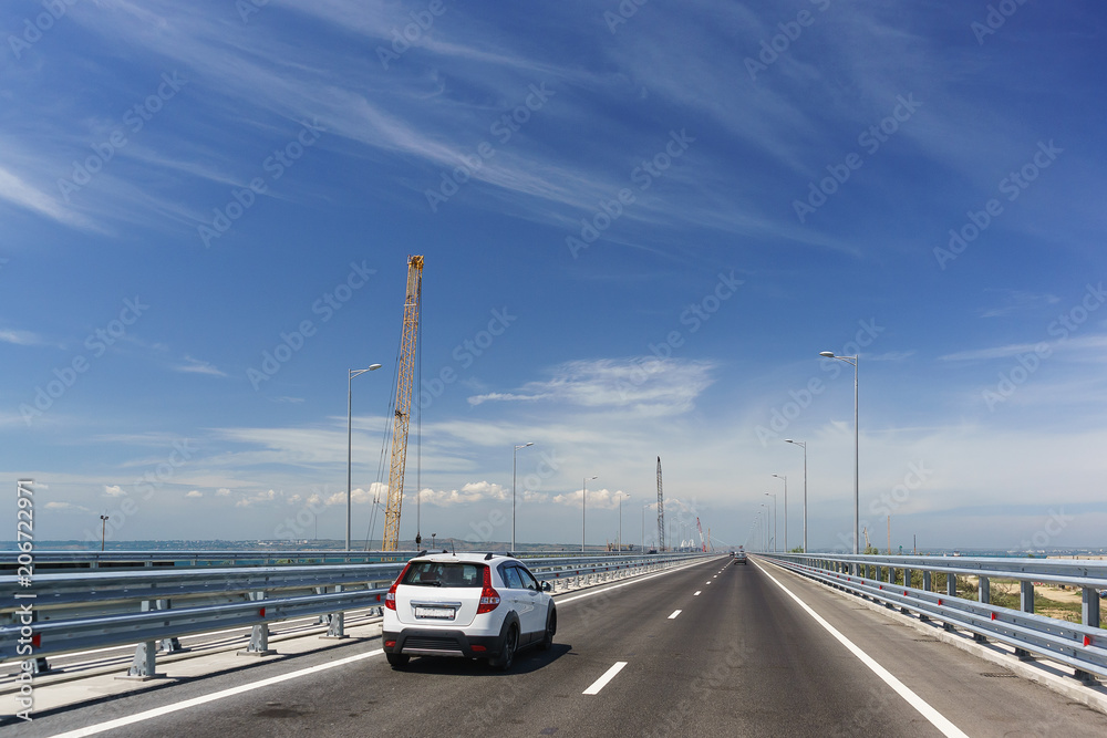 Cars driving on the Tuzla spit on the Taman Peninsula. Crimean bridge on a Sunny day