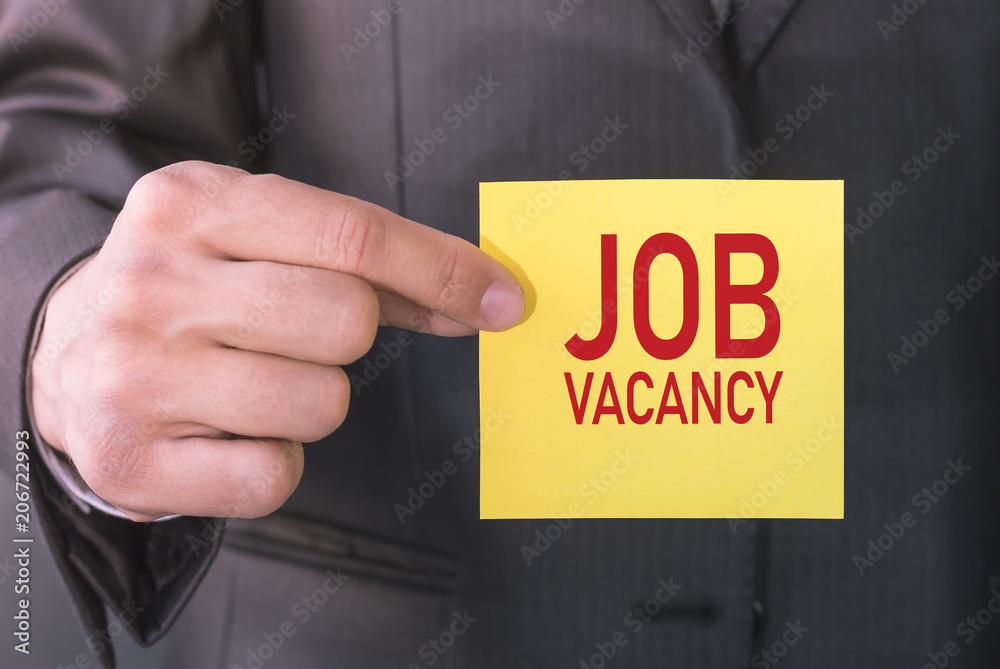 Closeup businessman holding card with text JOB VACANCY Closeup businessman holding card with text JOB VACANCY