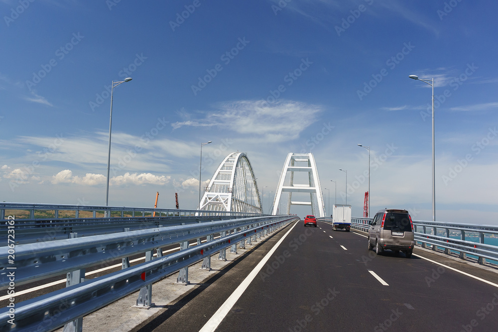 Cars on the Crimean bridge drive up to the white metal arches over the fairway