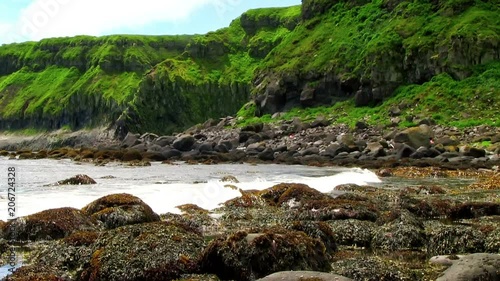 Okhotsk Sea, Iturup Island, Russia. Sea waves break up on coastal rocks covered with algae. 