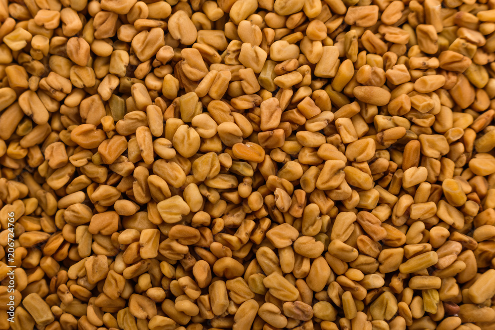 fragrant grains of fenugreek on a rustic background fragrant grains of fenugreek on a rustic background