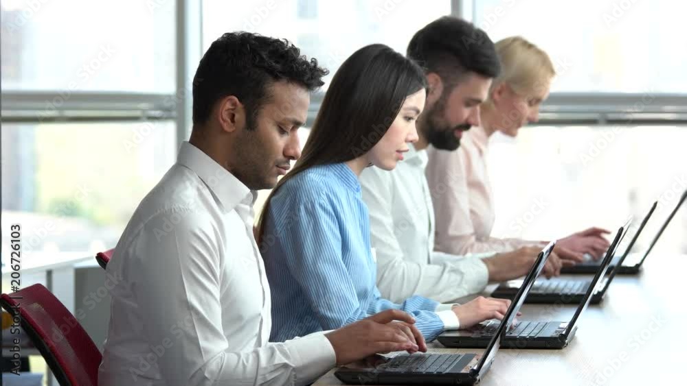 Busy people working in office. Team of workers typing on laptops, huge windows background. Busy people working in office. Team of workers typing on laptops, huge windows background.