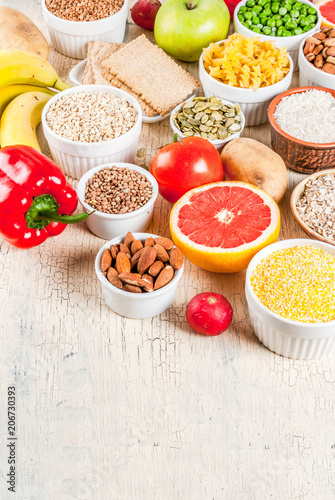 Diet food background concept, healthy carbohydrates (carbs) products - fruits, vegetables, cereals, nuts, beans, light concrete background copy space