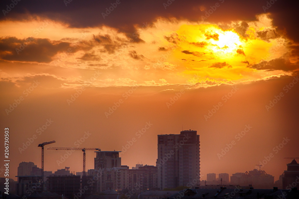 The sunset over the city is a bright orange sky, and lustrous clouds