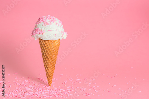 funny creative concept of wafer cone with ice cream covered and strewed sprinkles on pink background, copy space