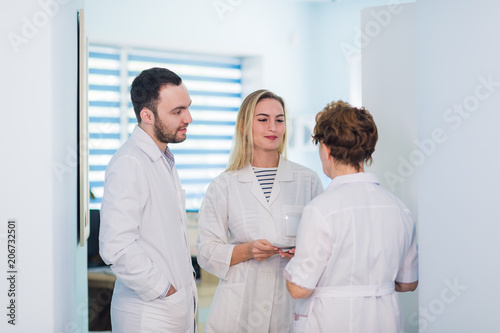 Fototapeta Naklejka Na Ścianę i Meble -  Group of senior doctors and young nurses examining medical report of patient. Team of doctors working together on patients file at hospital. Medical staff analyzing and working at clinic