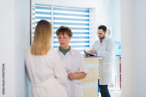 Mature doctor discussing with nurse in a hallway hospital. Doctor discussing patient case status with his medical staff after operation.