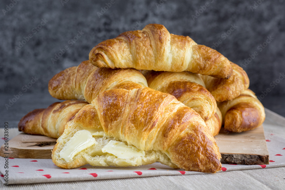 Gold butter croissant greased with butter on natural wood plank Gold butter croissant greased with butter on natural wood plank