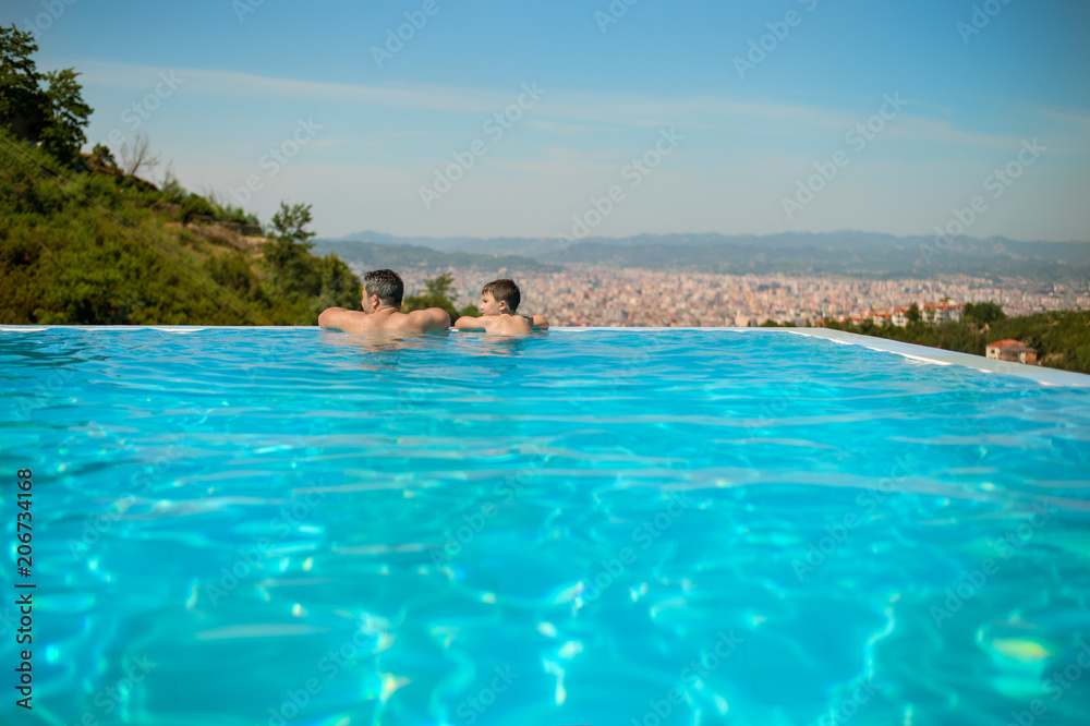 Happy family father and his little son at outdoors infinity swimming pool enjoying view of Tirana, Albania