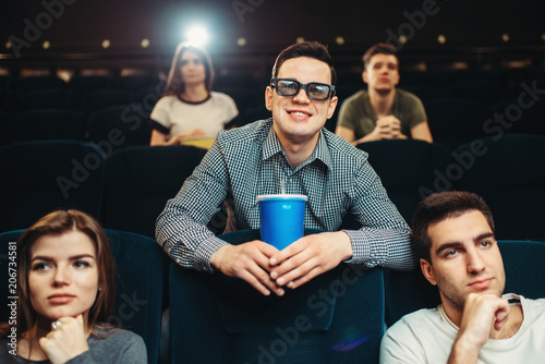 Smiling man in 3d glasses holds beverage in cinema