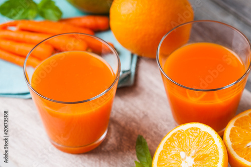 Glasses with carrot juice, apple, sliced orange and mint leaf 