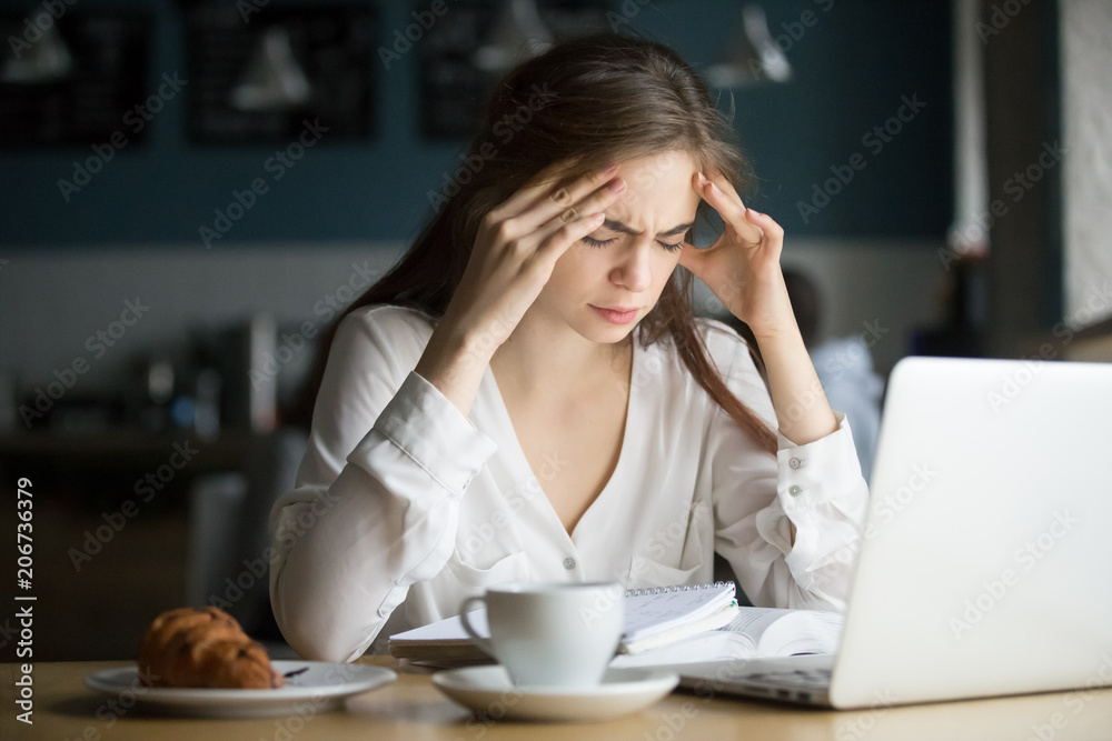 Nervous stressed woman feeling anxiety or strong headache massaging temples studying in cafe, young tired female student experiencing panic attack preparing for test or exam in public place Nervous stressed woman feeling anxiety or strong headache massaging temples studying in cafe, young tired female student experiencing panic attack preparing for test or exam in public place