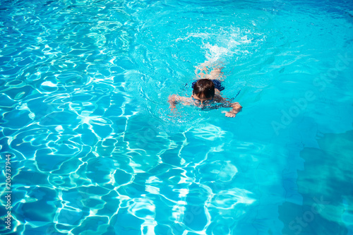 Child swim in the pool at the hotel. View from above.